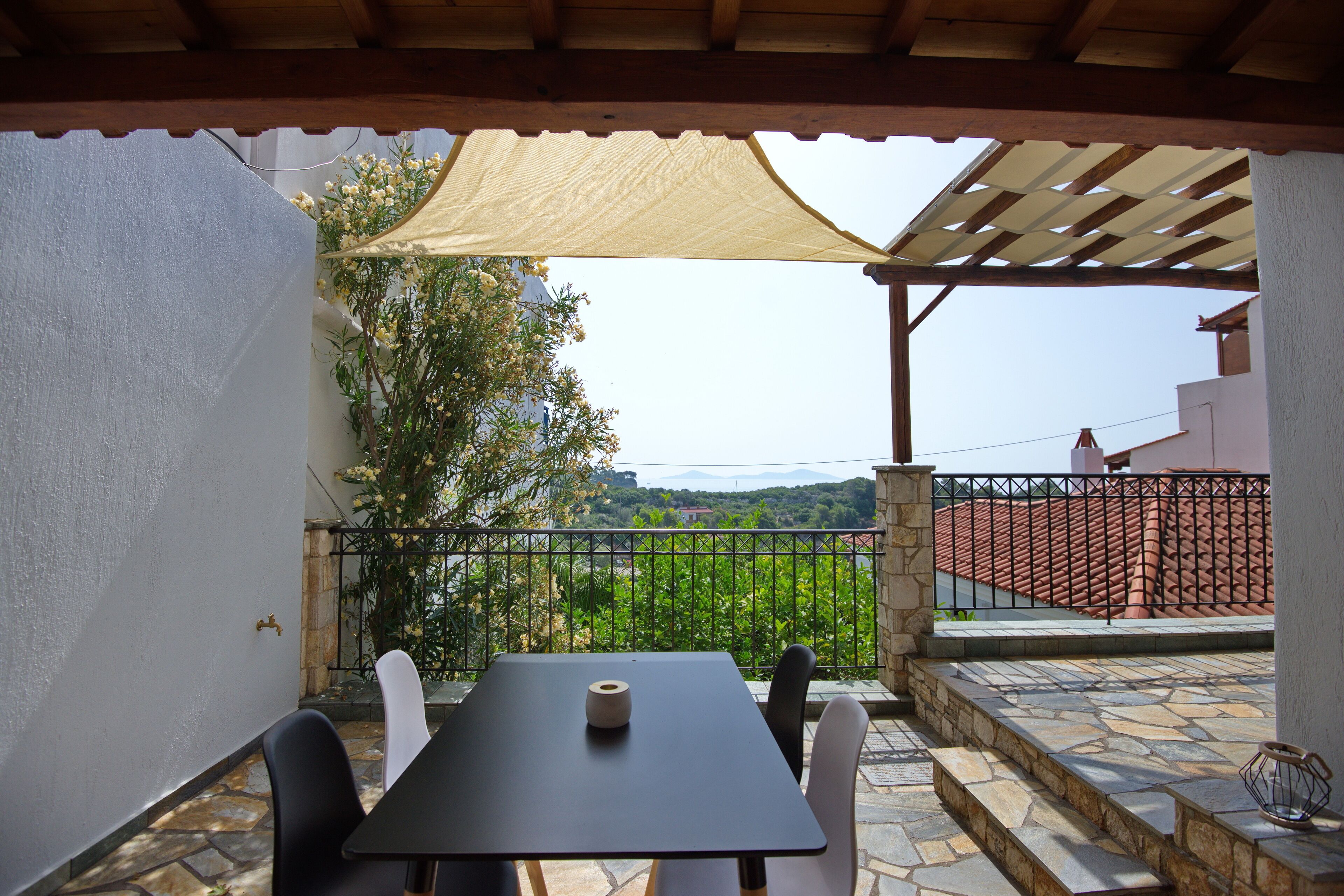Un espace extérieur aménagé, abrité et doté d’une table et de chaises, d’une pergola au-dessus et d’une vue sur une colline.