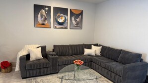 Una sala de estar moderna con un sofá modular, una mesa de centro de vidrio y arte abstracto en la pared.