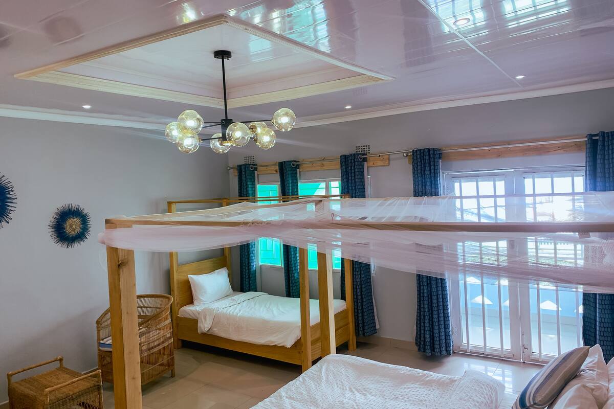 A room with bunk beds, a ceiling fan, and large windows with curtains.