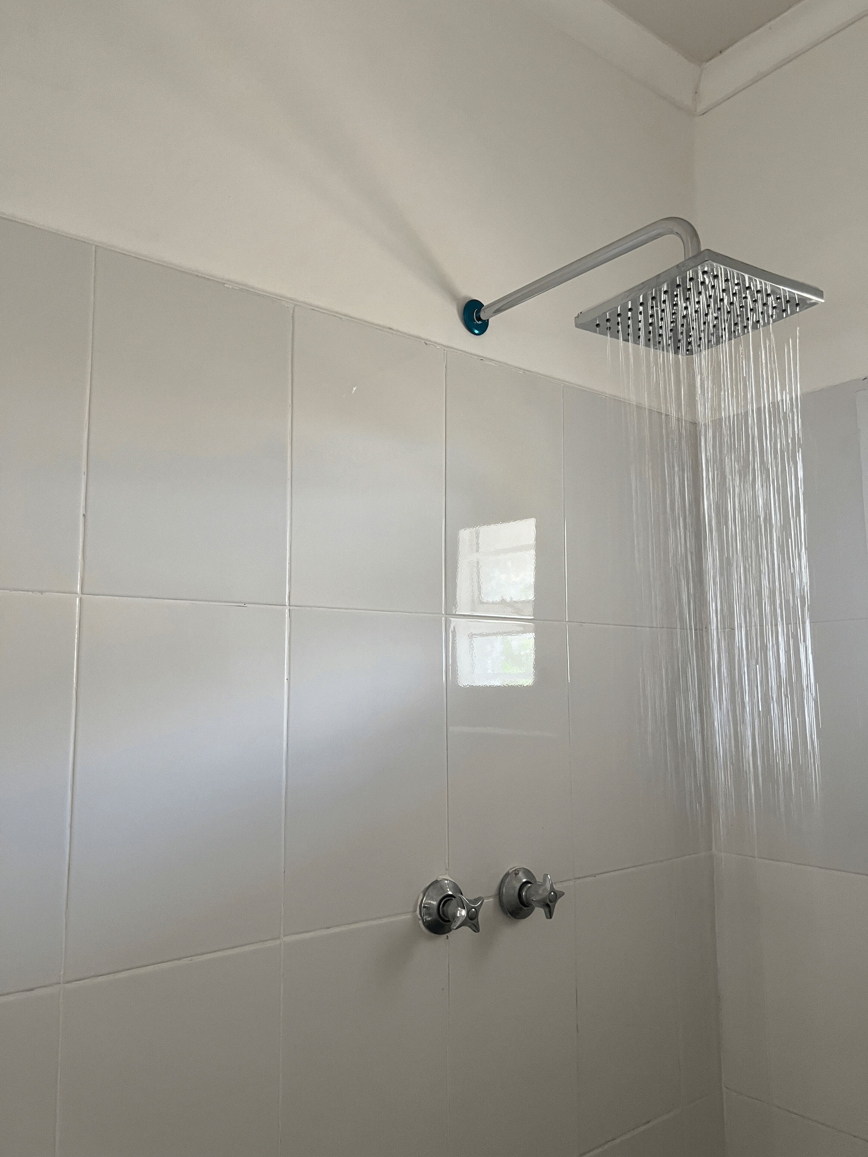 A shower with a modern design, featuring a rain showerhead and a handheld control.