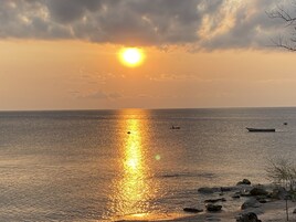 Un atardecer sobre un mar tranquilo con barcos y rocas.