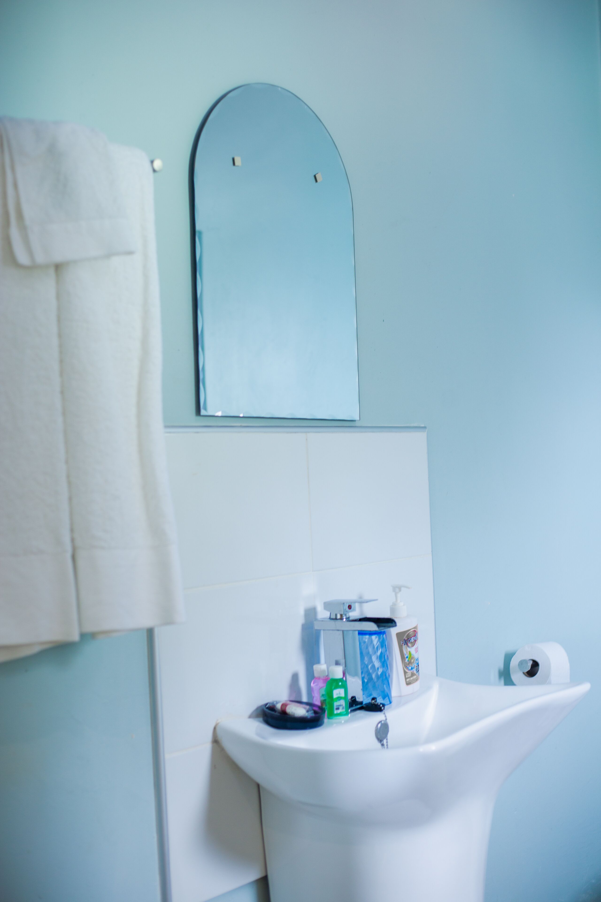 A bathroom with a white sink, a mirror, and a towel hanging on the wall.