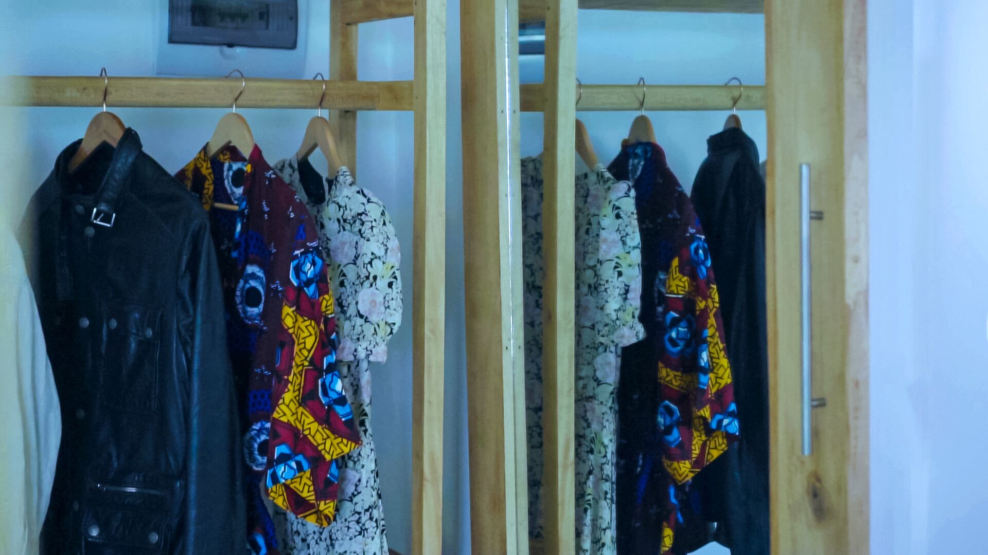 A wooden wardrobe with multiple hangers, each holding a garment.