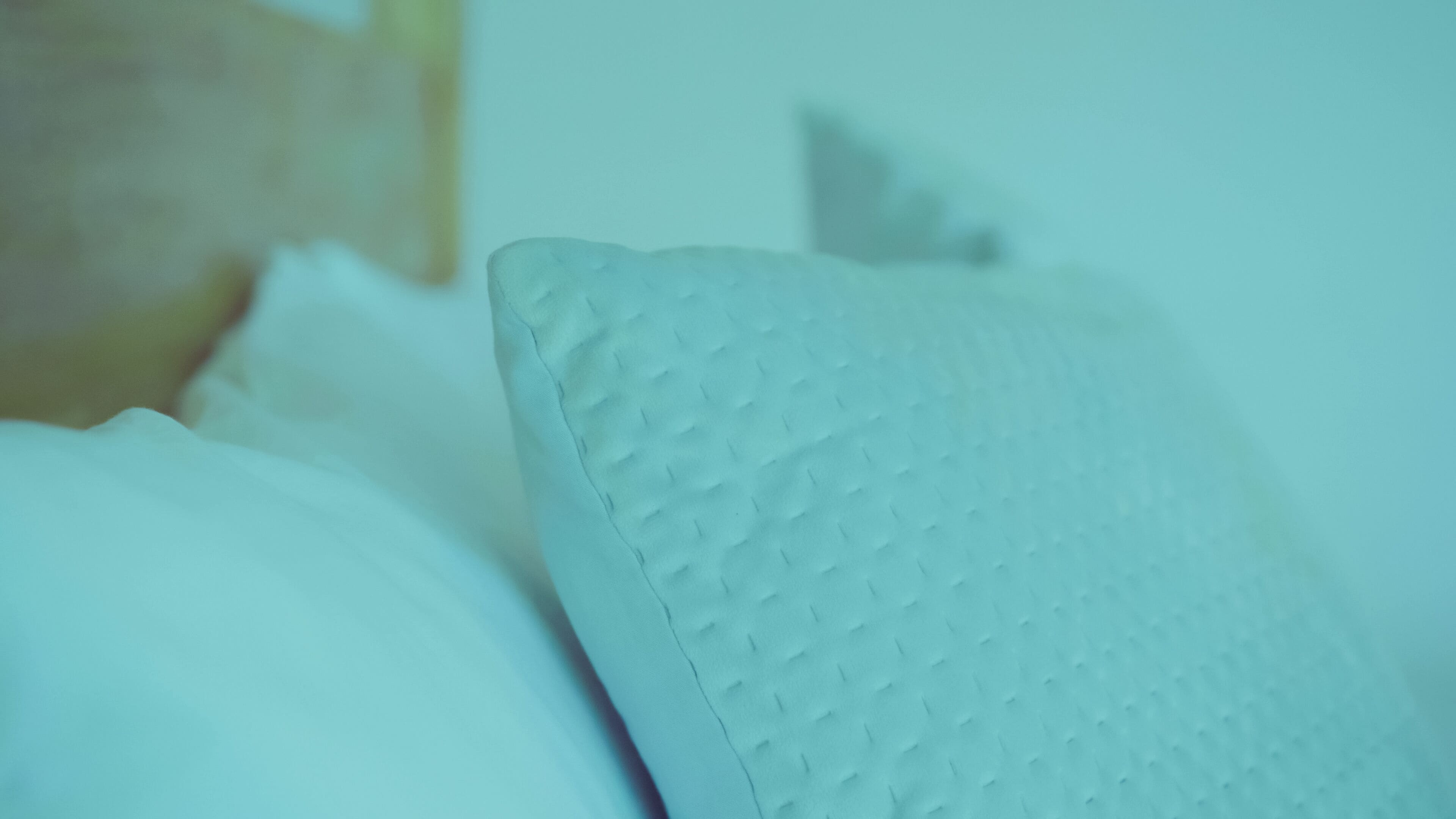 Ein Detailaufnahme eines strukturierten Kissens auf einem Bett.