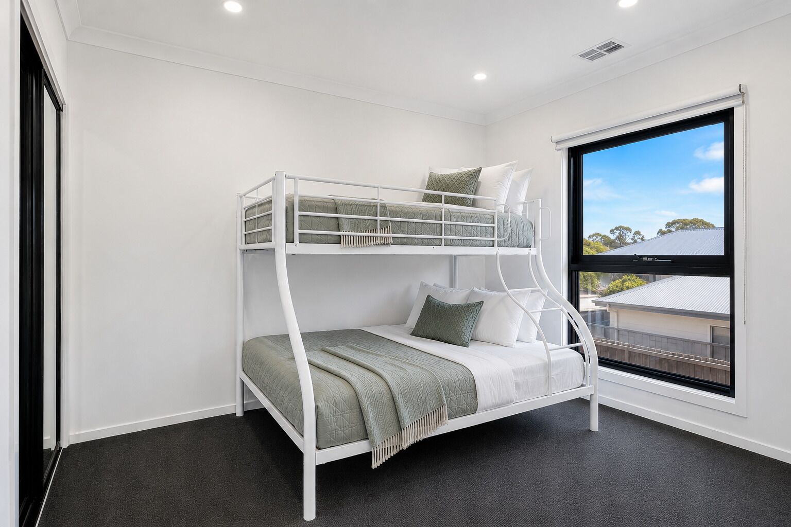 A bunk bed with a view of the outside through a window.