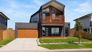 A modern two-story house with a large garage, a balcony, and a well-maintained lawn. - Island Family Retreat (Cowes)