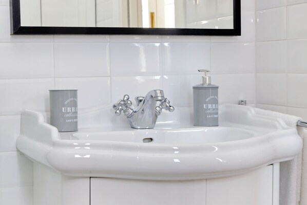A white bathroom sink with a modern faucet and two toiletry bottles. - Amazing penthouse in the heart of Rome (Roma)