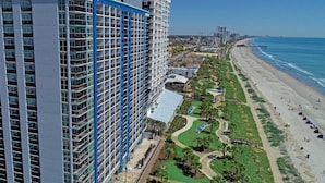 A high-rise hotel with multiple balconies, a beachside location, and a view of the ocean.