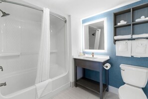 Un baño moderno con bañera, lavamanos, inodoro y espejo.
