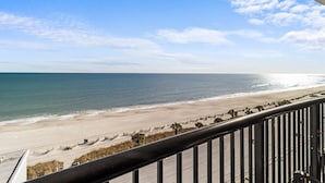 A beach view from a balcony with a railing, ocean, and clear sky. - Dazzzling Oceanfront Three Bedroom Condo 6th Floor (Myrtle Beach)