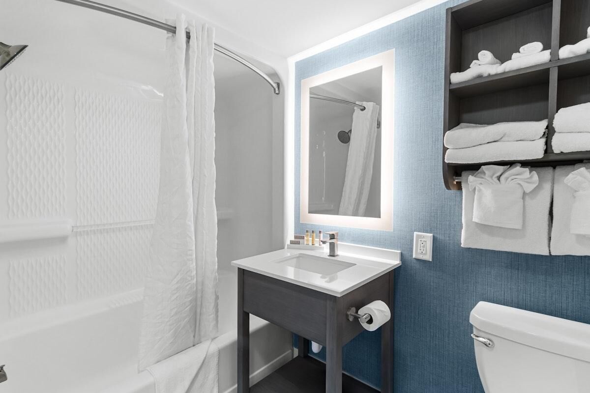 A modern bathroom with a shower, a sink, a toilet, and a towel rack.
