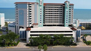 A multi-story hotel with a central atrium, a clock tower, and a view of the ocean. - Coastal Serenity: Ocean View 2 Bdrm Condo 15th Flr (Myrtle Beach)