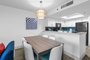 A modern kitchen with white cabinets, a black refrigerator, and a blue-tiled backsplash.
