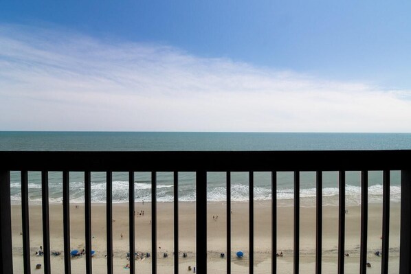 A beach view through a window with a railing.