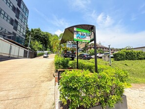 A paved walkway leading to a building with a signboard advertising a golf cart service.