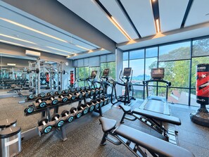 A gym with exercise equipment, a bench, and large windows offering a view.