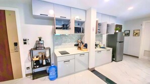 Una cocina moderna con armarios blancos, microondas integrado y refrigerador de acero inoxidable.