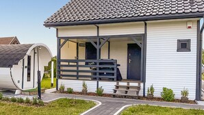 A single-story house with a tiled roof, a porch with a bench, and a small front yard with potted plants. - Stunning home in Jaromierz with sauna (Jaromierz)