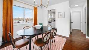 A dining area with a round table, six chairs, a chandelier, and a view of the outside. - NEW Barlow by the Bay 3BD Townhome Beaches Wineries (Traverse City)