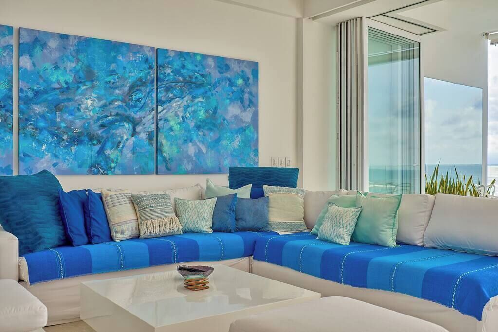 A modern living room with a sectional sofa, a coffee table, and a large abstract painting.