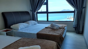 A hotel room with two beds, a nightstand, and a window with a view of the sea and a distant island. - Jesselton Quay 23A Sunset Seaview  (Kota Kinabalu)