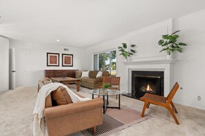 A spacious living room with a fireplace, a sofa set, a coffee table, and a dining area. - Pickleball | Putting Green | 5 BR | 3 mi to Disney (Anaheim)