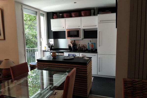 A modern kitchen with a glass dining table, white cabinets, and a black countertop.