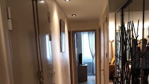Un couloir avec un plancher en bois, un radiateur et une porte sur le côté gauche.