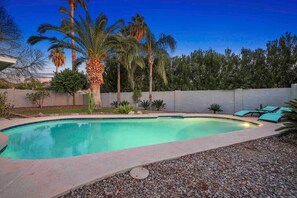 A swimming pool with a curved edge, surrounded by a pebble-lined deck. - Sahuaro Villa with Pool + Great Location (Scottsdale)