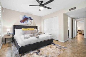 A bedroom with a bed, a ceiling fan, a nightstand, a lamp, and a painting on the wall. - Sahuaro Villa with Pool + Great Location (Scottsdale)