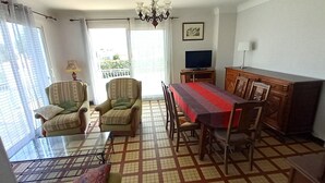Un espace repas comprenant une table, des chaises, un téléviseur et un meuble.