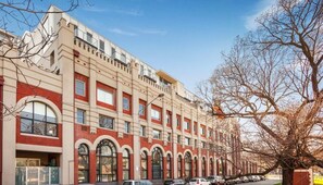 A multi-story building with a symmetrical facade, large arched windows, and a flat roof.