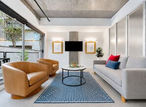A modern living room with leather sofas, a coffee table, and a flat-screen TV mounted on the wall. - The Powlett by Ready Set Stay- East Melbourne (East Melbourne)
