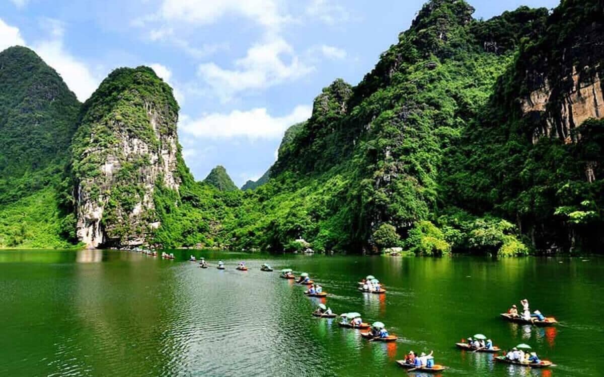 A group of boats on a river surrounded by lush green mountains.