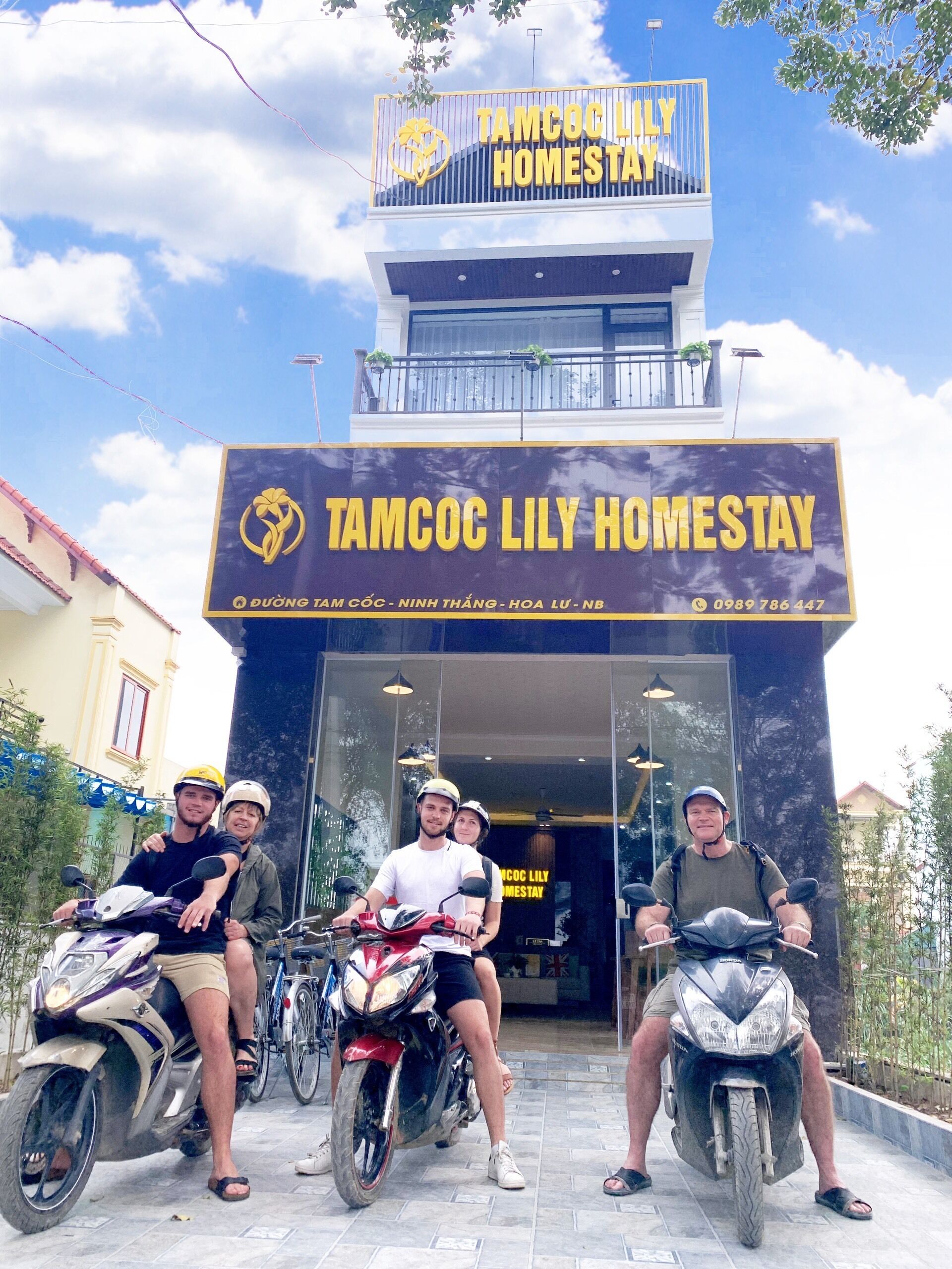A building with a sign reading "TAMCOC LILY HOMESTAY" and a contact number.