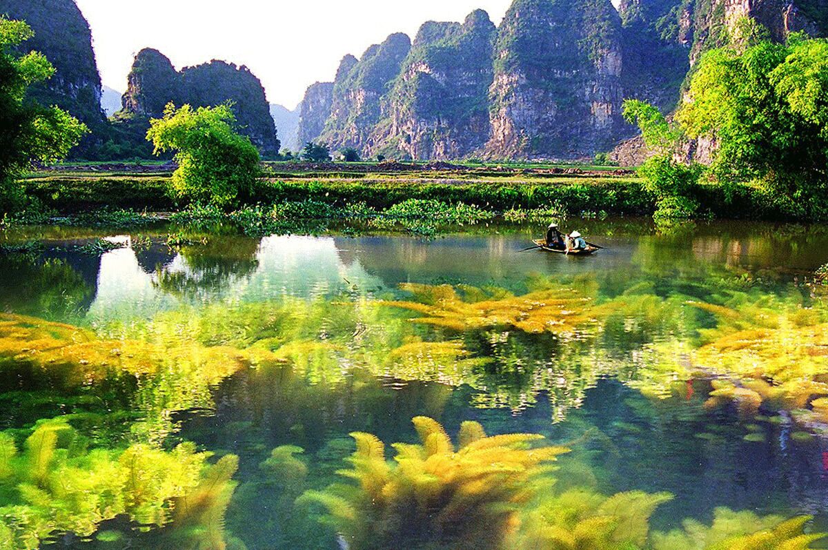 A calm river with a boat and lush greenery.