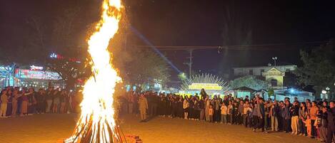 Un gran espectáculo de fuego en un espacio abierto, con una multitud de personas reunidas alrededor.
