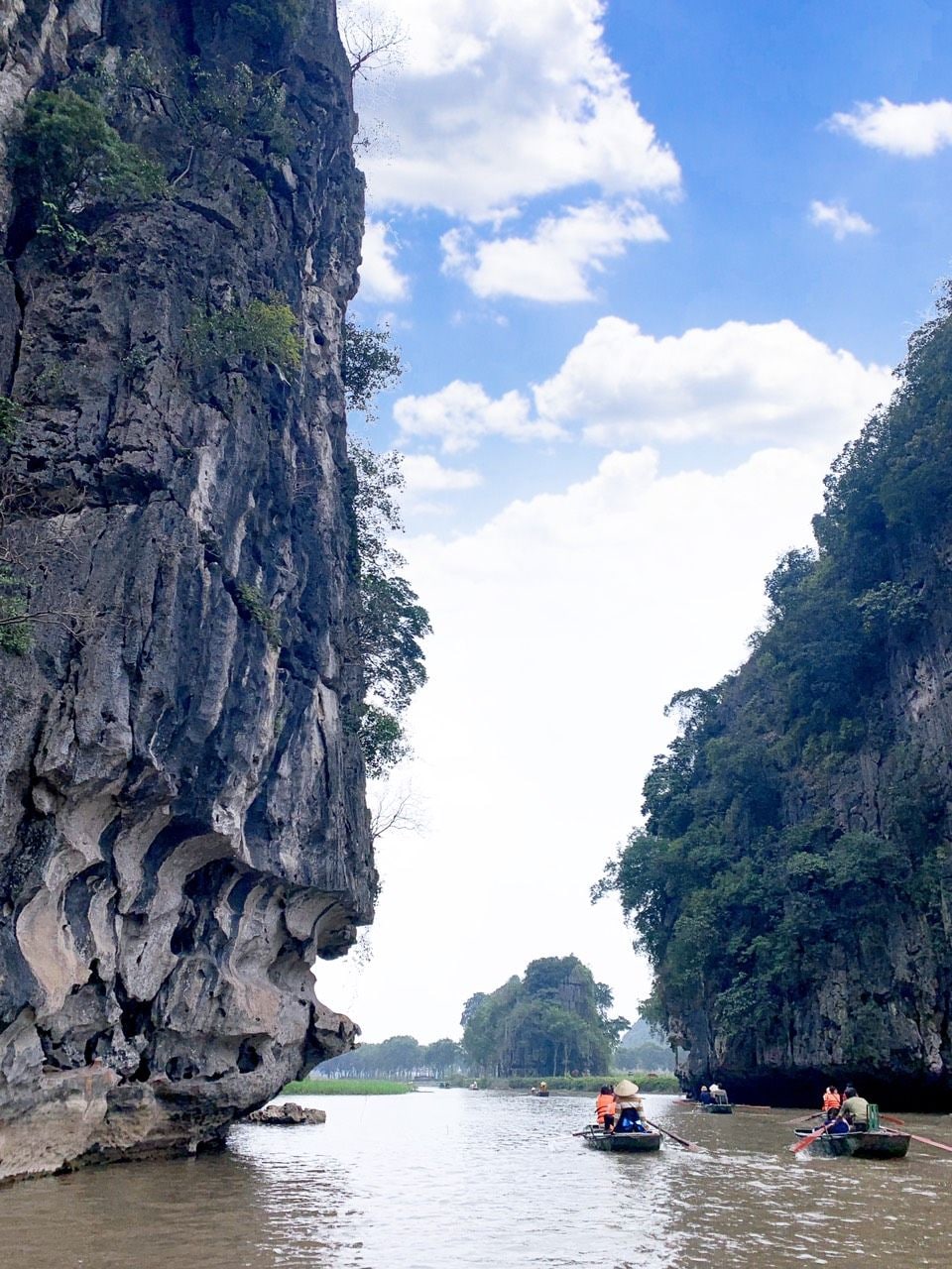A river with boats and a rocky cliff.