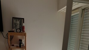 Une pièce avec une bibliothèque en bois, une photo encadrée et une fenêtre avec des stores.