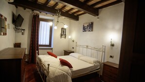 A bedroom with a double bed, wooden headboard, bedside tables, a dresser, a TV mounted on the wall, and a window with curtains. - House of the Olive Grove (Narni Sotterranea with free parking) (Narni Scalo)