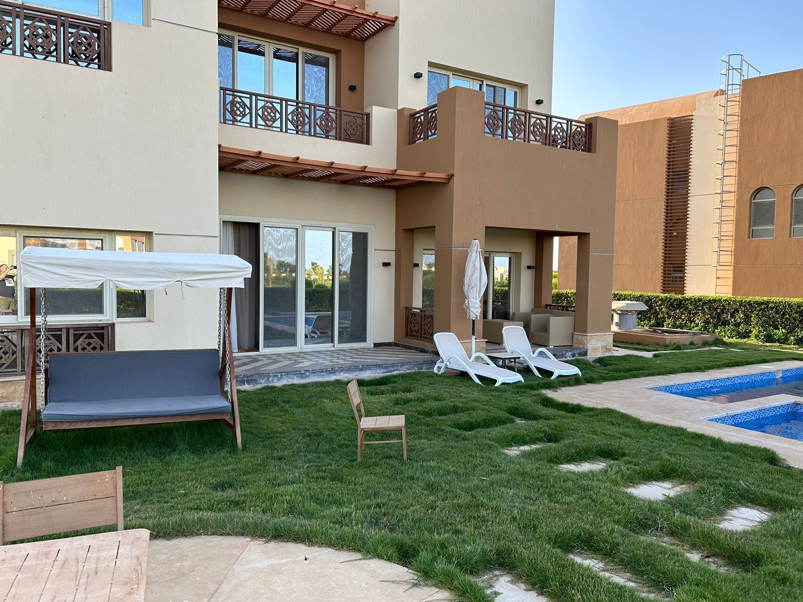 A modern building with a swimming pool, outdoor seating, and a covered seating area.