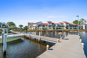 Ein Hotel am Wasserufer mit einem Steg, einem Boot und einer Reihe von Gebäuden mit roten Dächern.