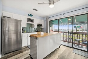 A modern kitchen with a stainless steel refrigerator, white cabinets, and a wooden countertop.