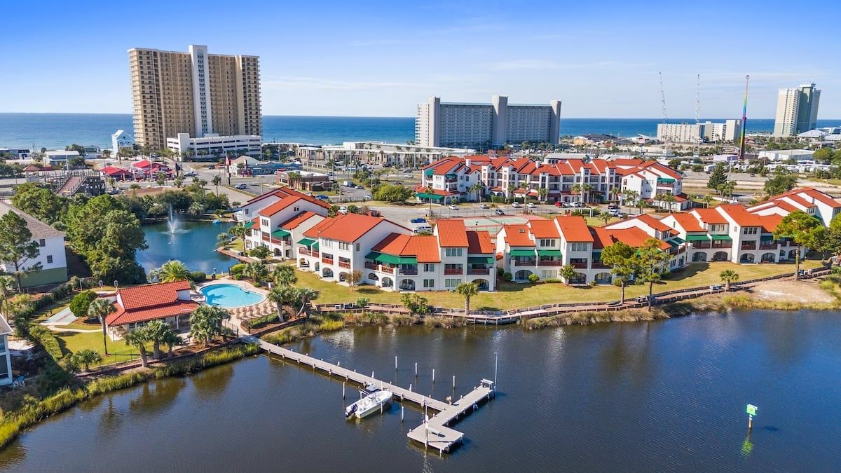 Un hotel costero con varias edificaciones, un puerto deportivo y una gran extensión de agua.