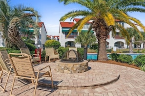 A poolside area with lounge chairs, a fire pit, and a pool.