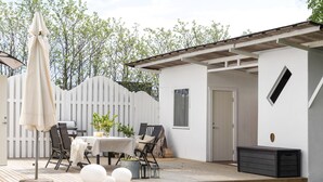 A patio with a table, chairs, and a grill.