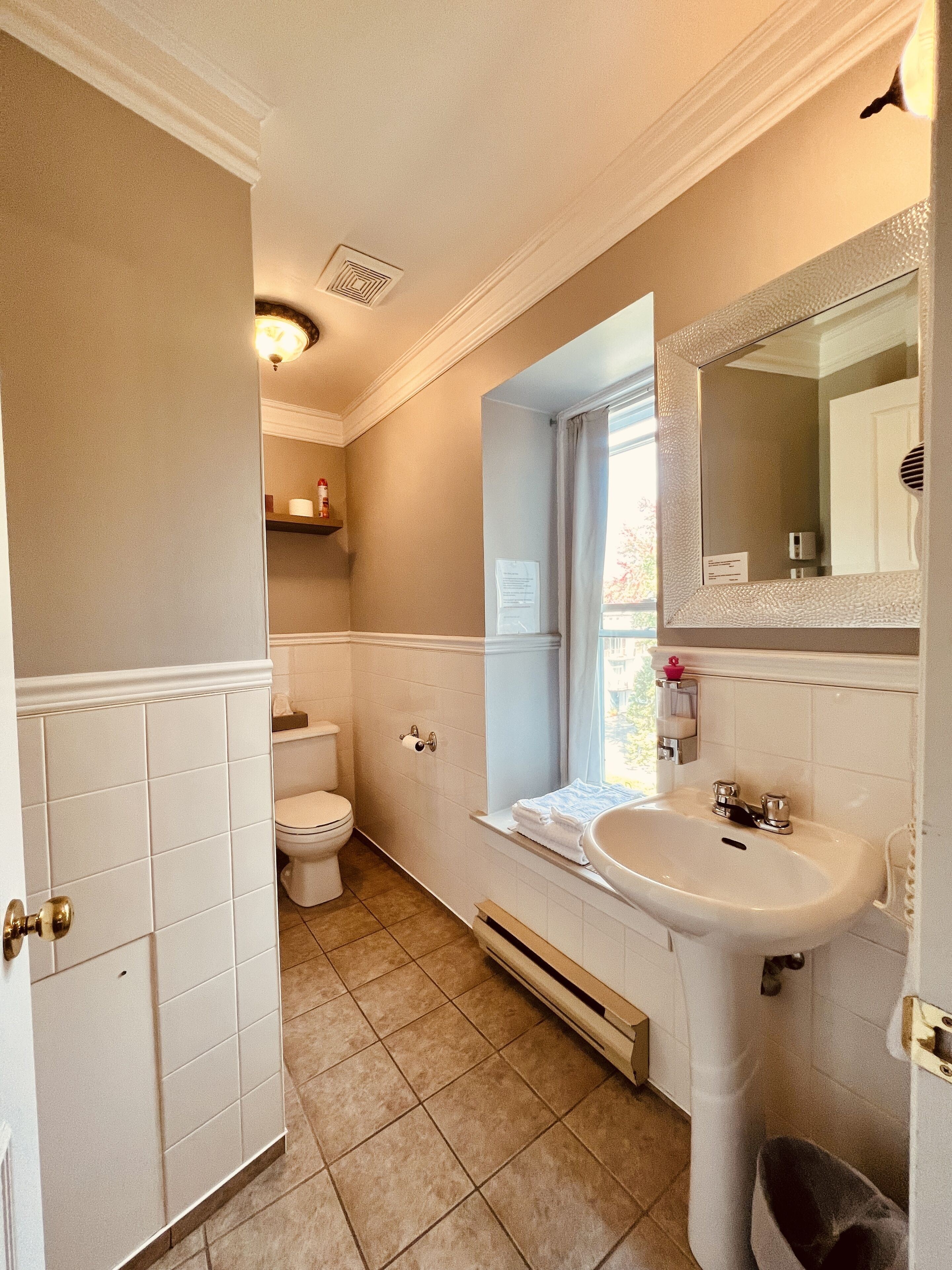 Une salle de bain avec des toilettes, un lavabo et une fenêtre.