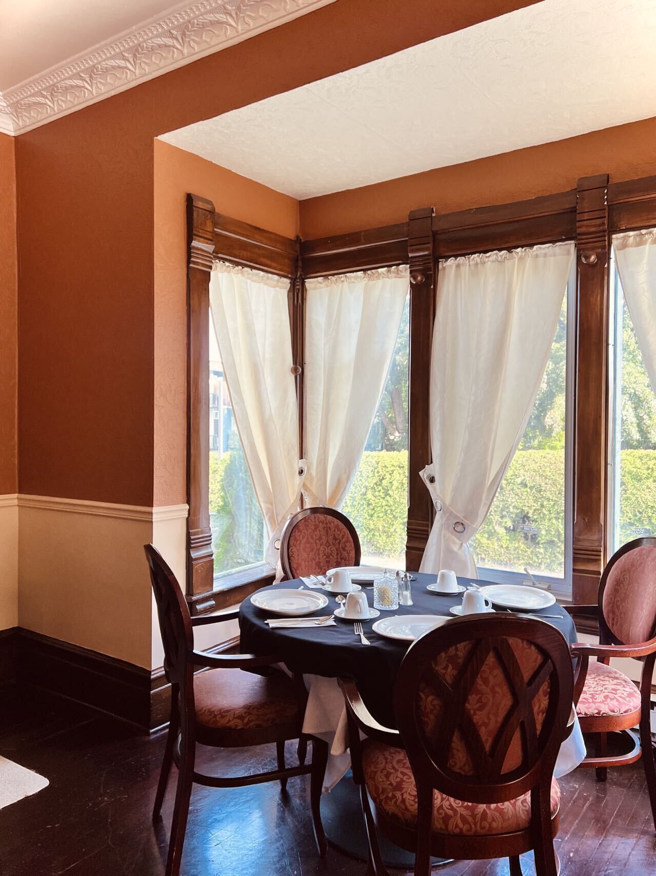 A dining room with a round table set for four, surrounded by upholstered chairs.