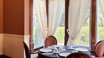 A dining room with a round table set for four, surrounded by upholstered chairs.