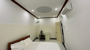 A hotel room with a bed, a desk, a chair, and an air conditioning unit. - Ninh Chu House (Ninh Chu)